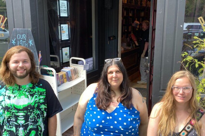 Tres personas frente a una librería con un cartel de pizarra. 5