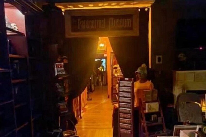 A dimly lit corridor with a sign reading 'Famous Museum' and a person in a yellow shirt standing near a counter. 2