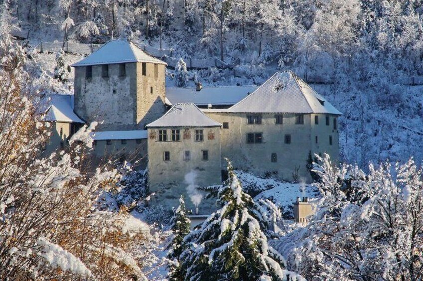 A snow-covered castle with multiple towers, surrounded by snow-laden trees and a hilly landscape. 3