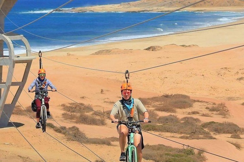 Due persone su un percorso in buggy delle dune in un paesaggio desertico, con una spiaggia sullo sfondo. 5