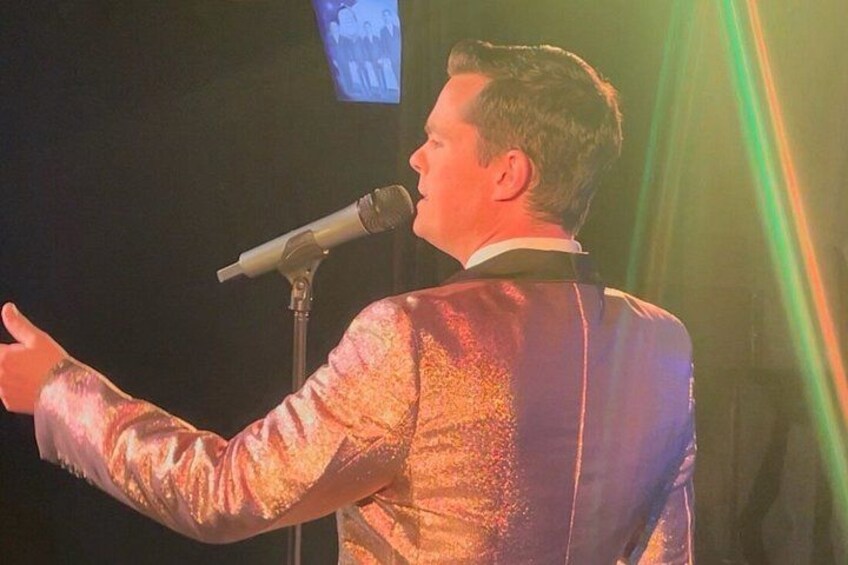 Eine Person in einer glänzenden, reflektierenden Jacke spricht in ein Mikrofon. 2