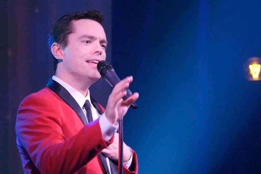 Une personne vêtue d’un costume rouge, tenant un microphone. 3