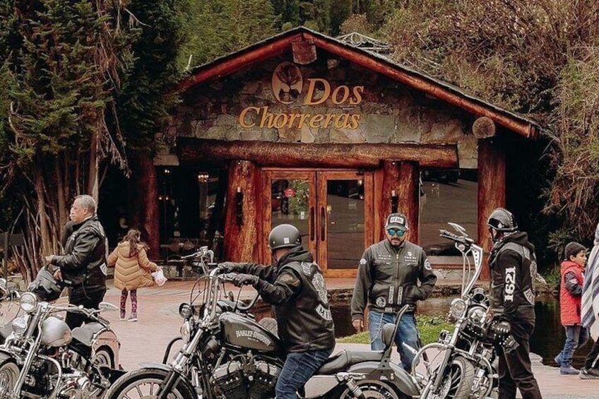 Un edificio rústico de madera con el letrero 'Dos Chorreas' y varias motocicletas estacionadas al frente. 3