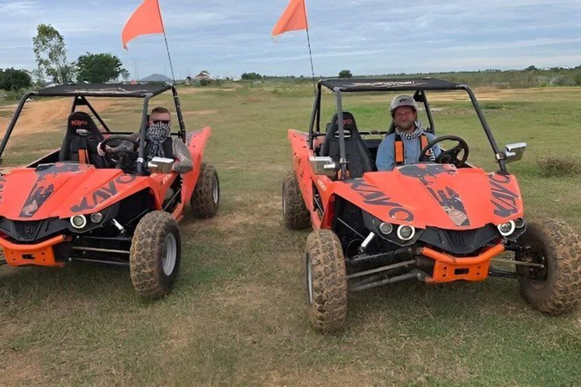 Two orange off-road vehicles with flags on a grassy field. 2