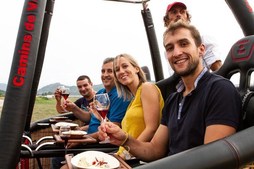 People enjoying a meal and drinks in a vehicle with 'Camins de Vau' written on the side. 3