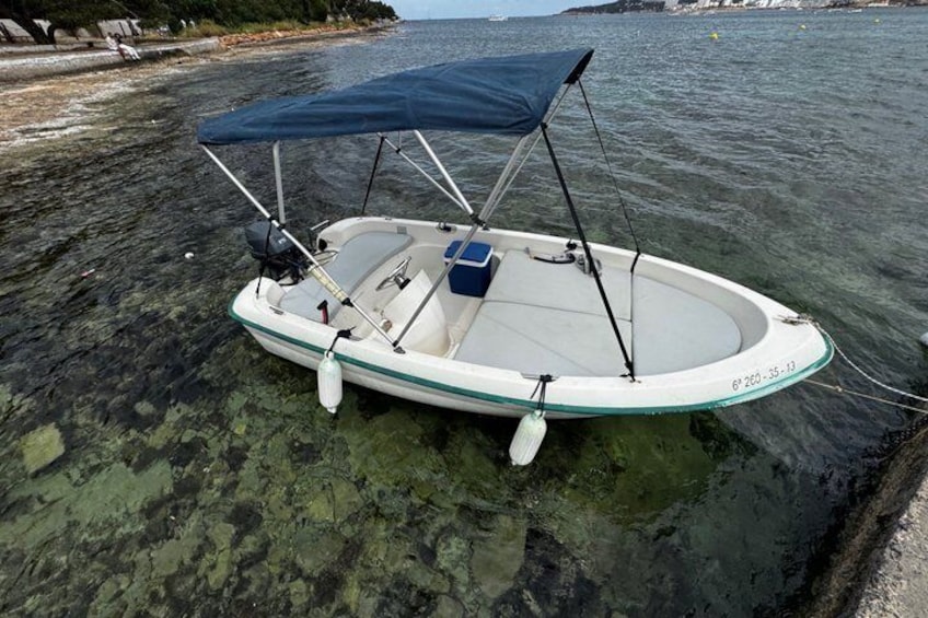 A small boat with a canopy, anchored near a rocky shoreline. 3