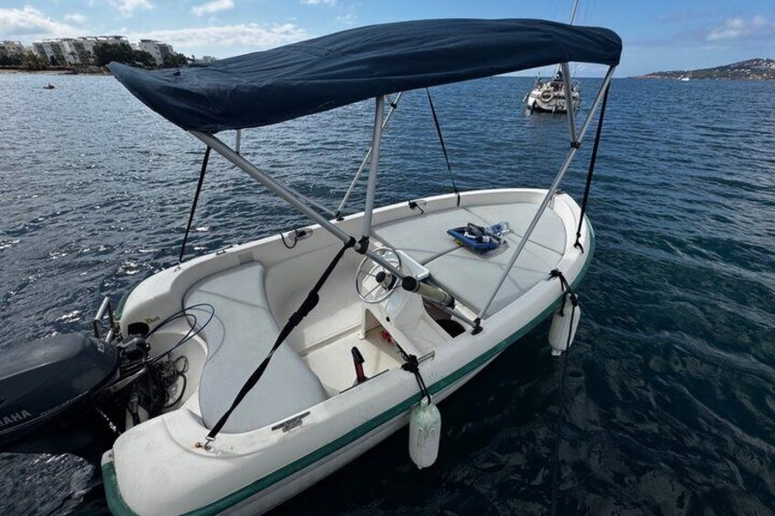 A small white boat with a blue canopy, docked in calm waters. 5