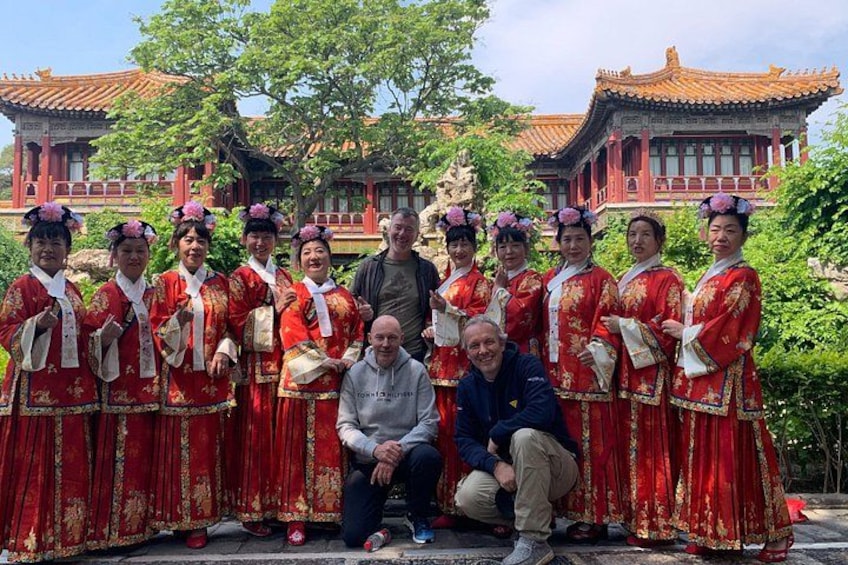 A group of people in traditional red attire posing in front of a temple with red architecture. 5