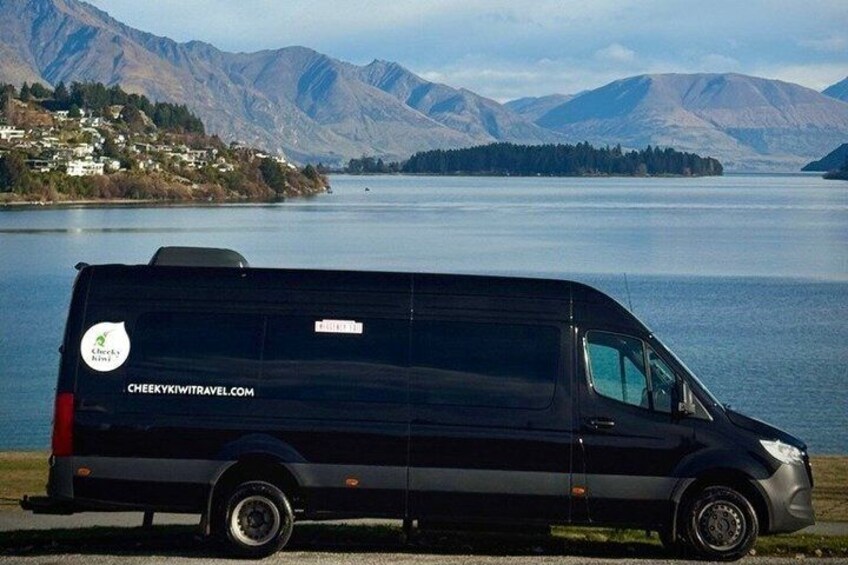 A black van parked by a lake with mountains in the background. 3