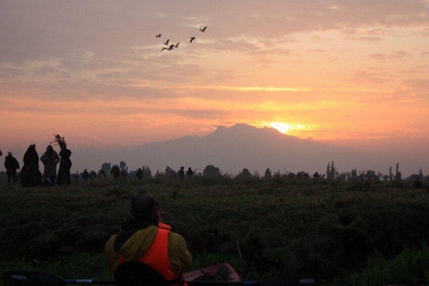 A sunset with silhouettes of people and birds against a mountain backdrop. 5