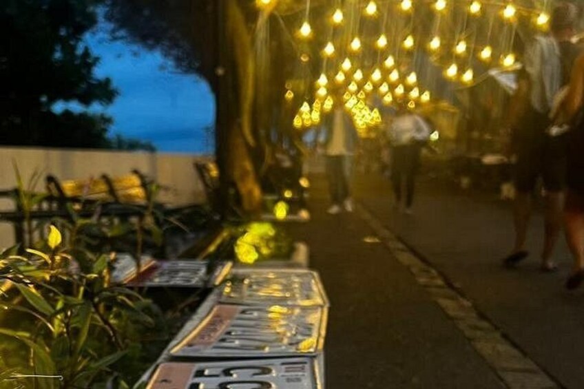 A street with hanging lights and a table with a sign. 3