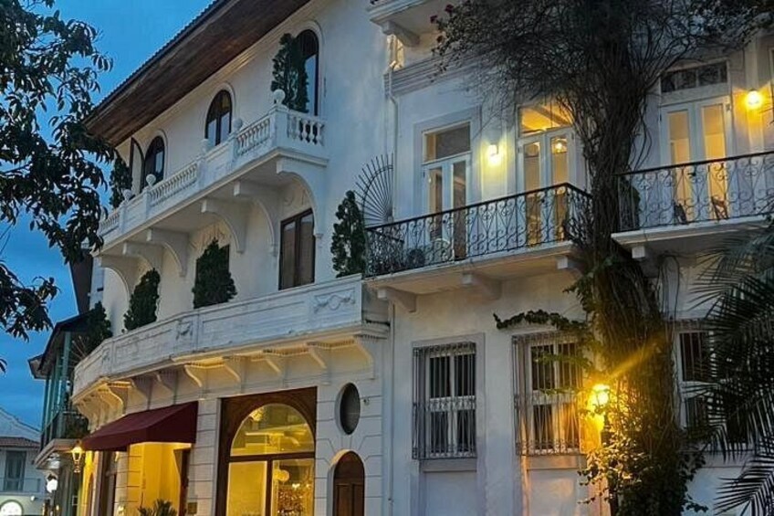 A multi-story building with balconies, arched windows, and a red awning. 4
