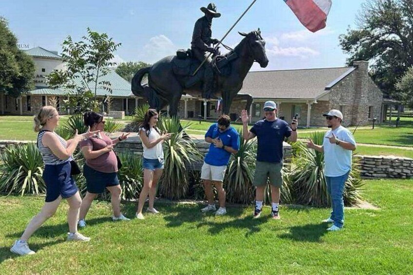 A group of people standing in front of a statue of a person on horseback. 4