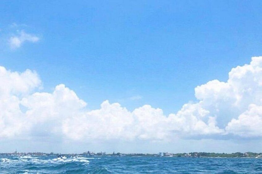 A coastal landscape with a clear sky, large clouds, and a view of the sea. 3