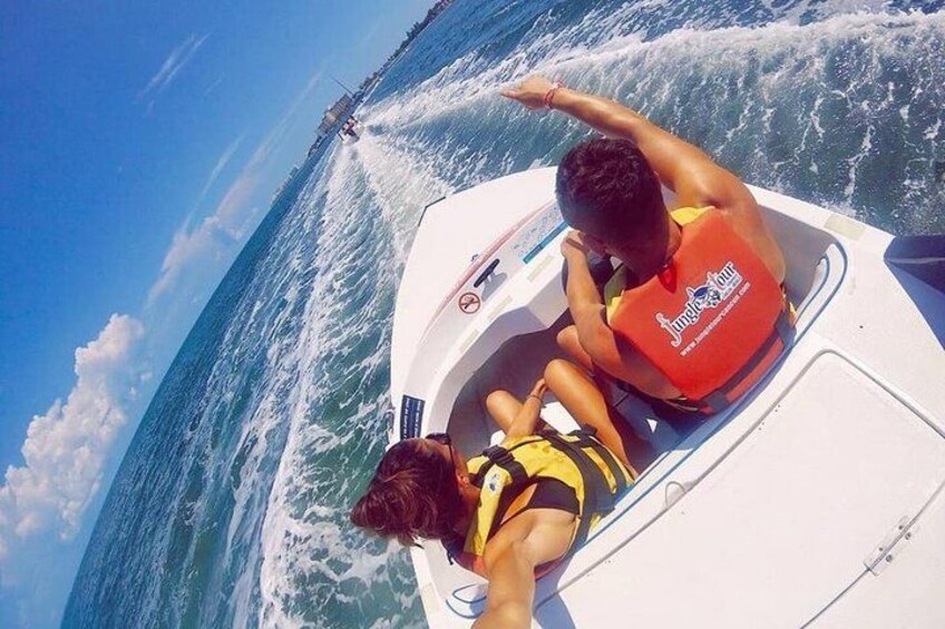 Two people on a boat, one wearing a life jacket, with waves in the background. 2