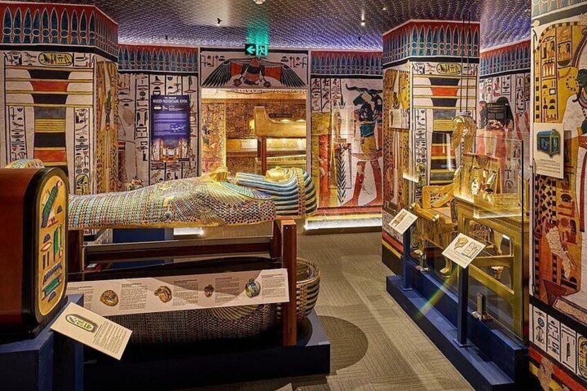 An Egyptian-themed exhibit with a bed, mummy, and wall decorations. 5