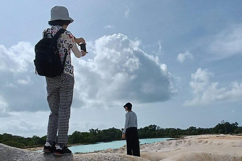 Dos personas están de pie en una playa con cielo nublado y una masa de agua al fondo. 1