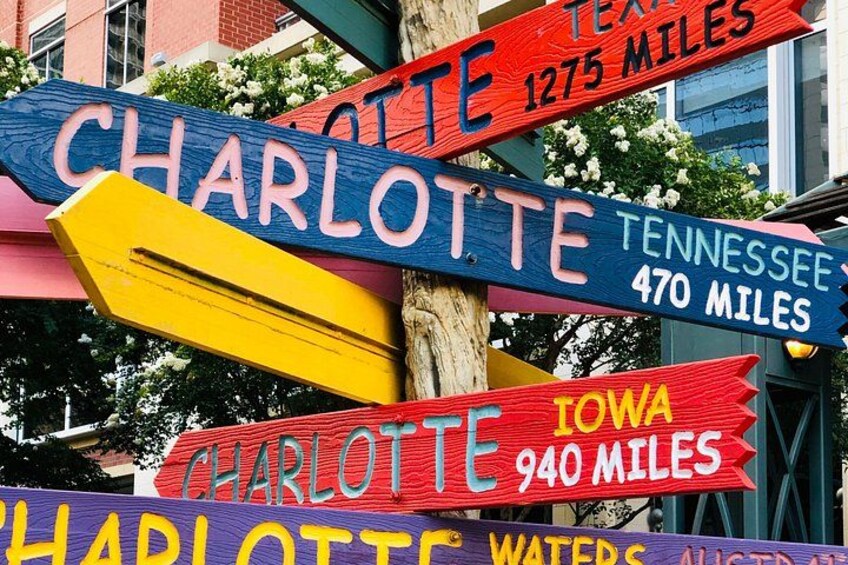 A colorful signpost with directional signs to various locations including Charlotte, Tennessee, Iowa, and Texas. 3