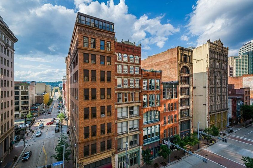 A city street lined with historic buildings, a clear sky, and a distant mountain range. 3