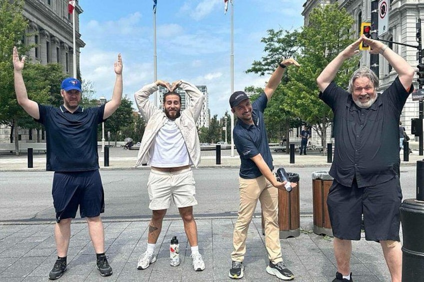 Four people standing on a sidewalk, one holding a phone. 2