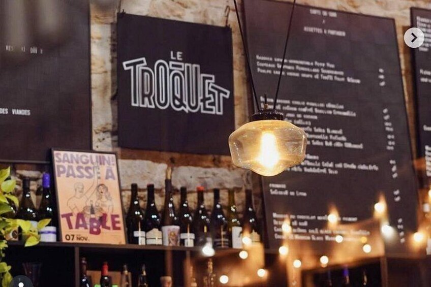 A bar with a menu board, wine bottles, and a hanging light fixture. 4