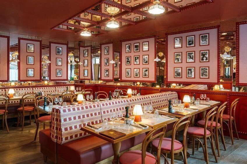 A restaurant interior with red walls, framed pictures, wooden tables, and cushioned booths. 2