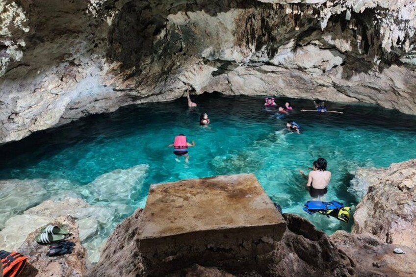 A group of people swimming in a natural pool surrounded by rocky cliffs. 1