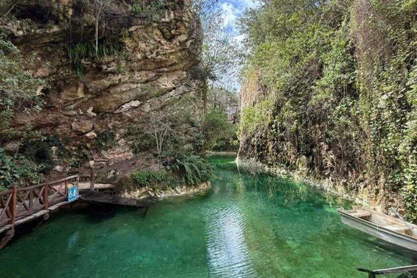 Un río cristalino con un puente de madera, acantilados rocosos y abundante vegetación. 1