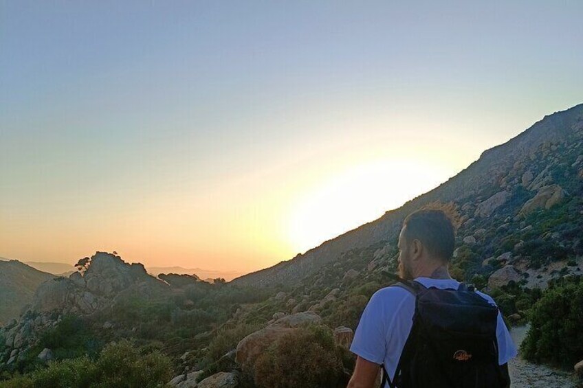 A person hiking on a rocky trail with a sunset in the background. 3