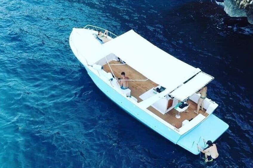 Un petit bateau bleu clair, doté d’un auvent blanc, d’un pont en bois et d’une personne pêchant à l’arrière. 3