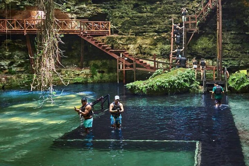 Personas caminando sobre un puente de madera que cruza un río, rodeado de vegetación. 2