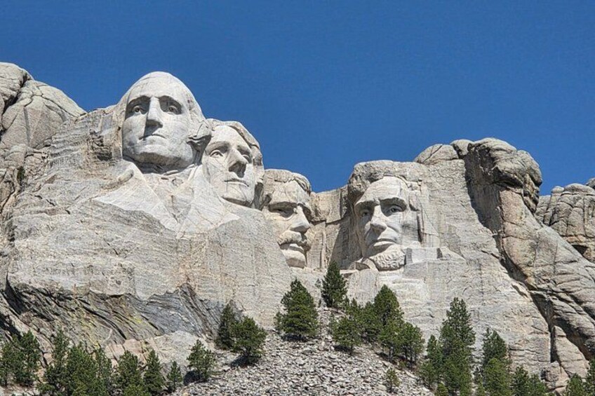 Mount Rushmore with four large stone faces carved into the mountain. 1