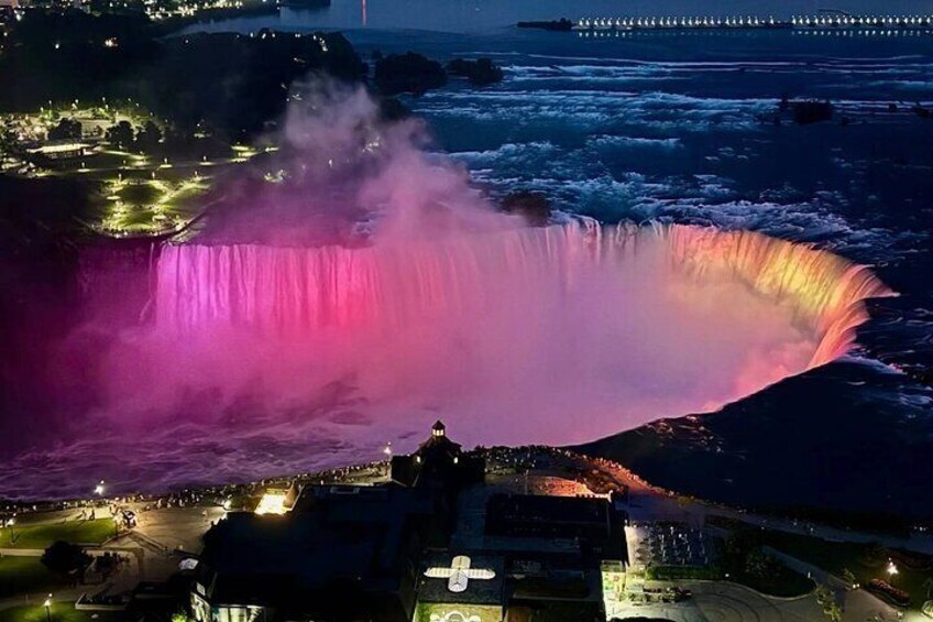 Une grande cascade aux reflets rosés, une plateforme d’observation et un quai situé au loin. 1
