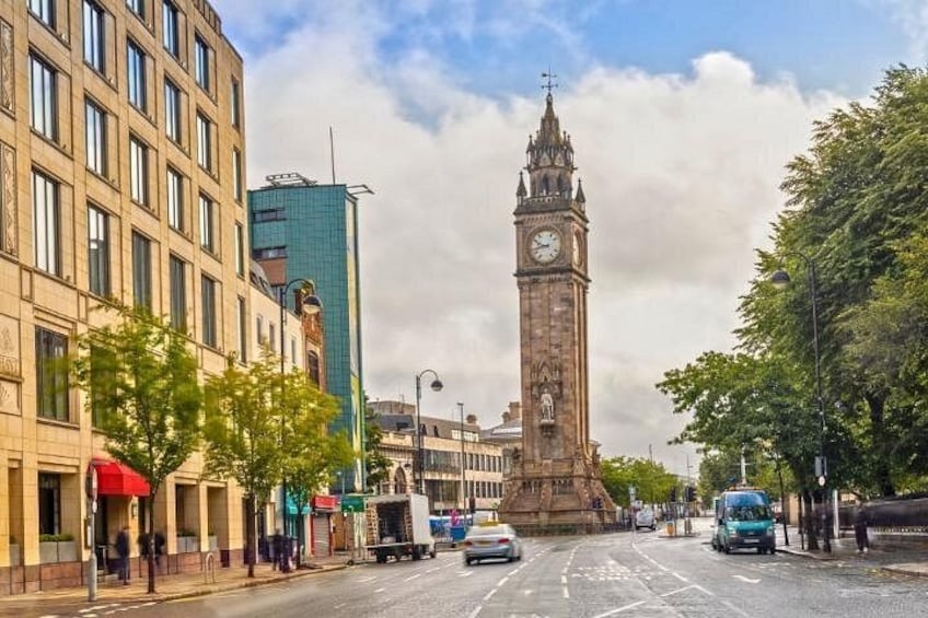 A historic clock tower, modern buildings, and a street with cars and pedestrians. 2