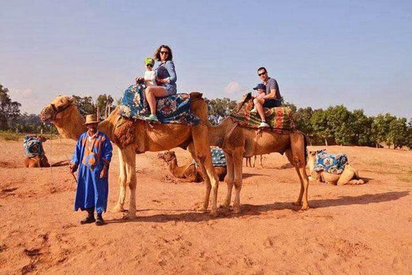 A desert landscape with camels and people riding them. 5