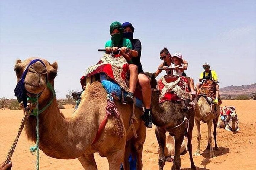 A group of people riding camels in a desert landscape. 3