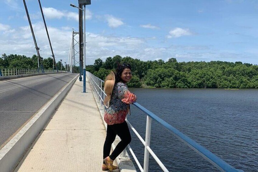 A person walking on a bridge with a river and greenery in the background. 5