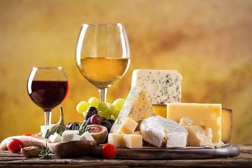 Une variété de fromages, de raisins et de verres à vin sont disposés sur une surface en bois. 1