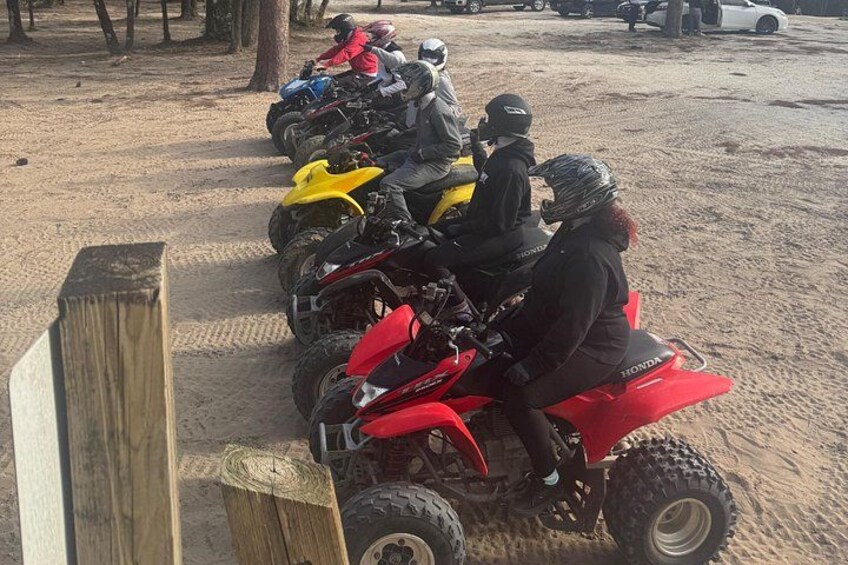 A row of quad bikes parked on sandy ground. 3