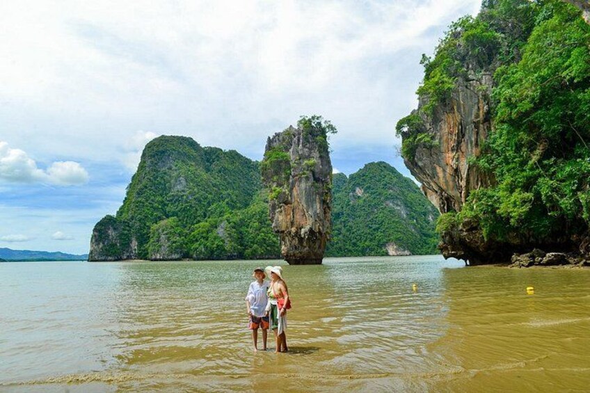 A couple standing in shallow water with limestone cliffs in the background. 2