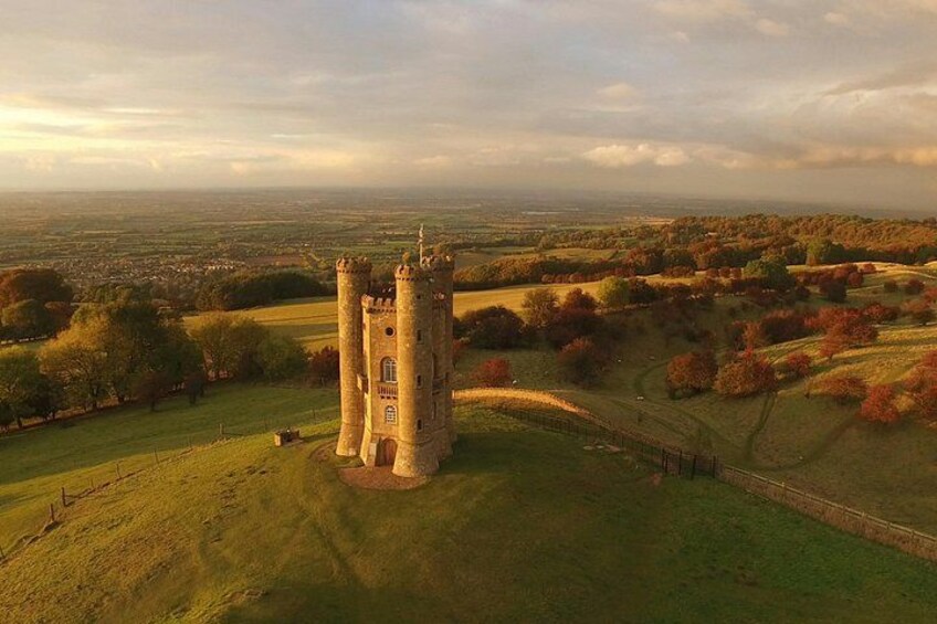 A tower in a grassy field with a distant view of a town. 3