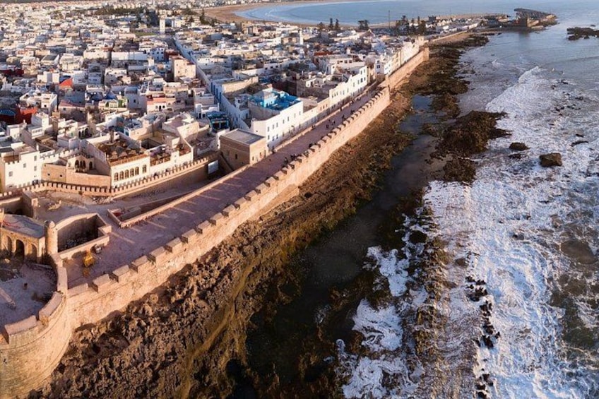 A coastal city with a fortified wall, a beach, and a rocky shoreline. 1