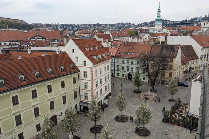 Una piazza storica europea con edifici tradizionali, un'imponente torre campanaria e un pavimento in pietra. 2