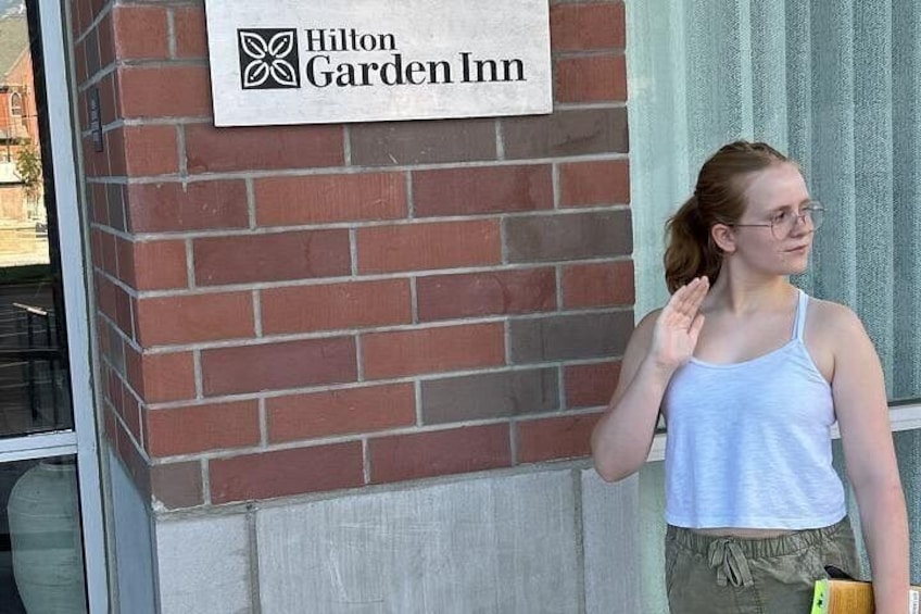 A person standing in front of a Hilton Garden Inn sign. 3