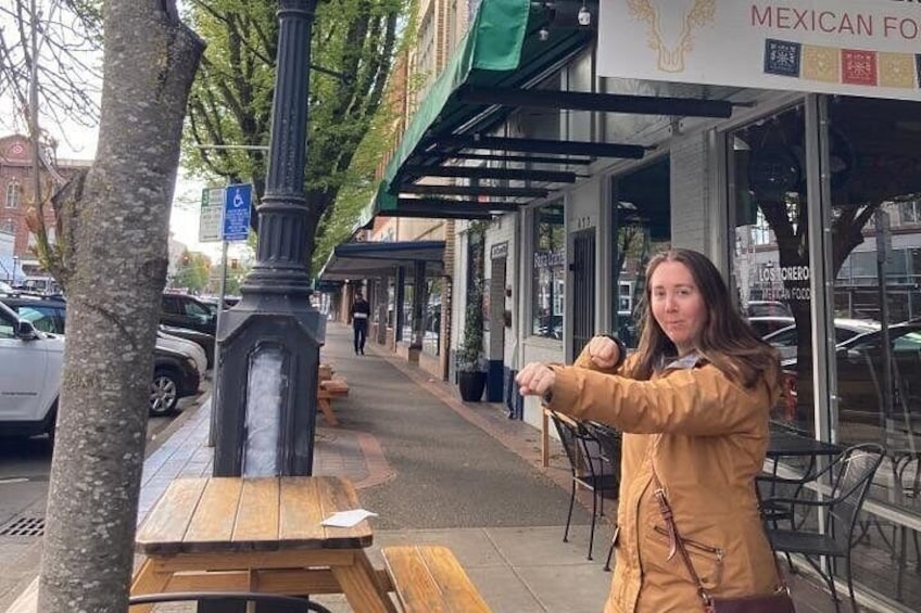 A person sitting at a wooden table outside a restaurant with a sign that reads 'MEXICAN FOOD.' 5