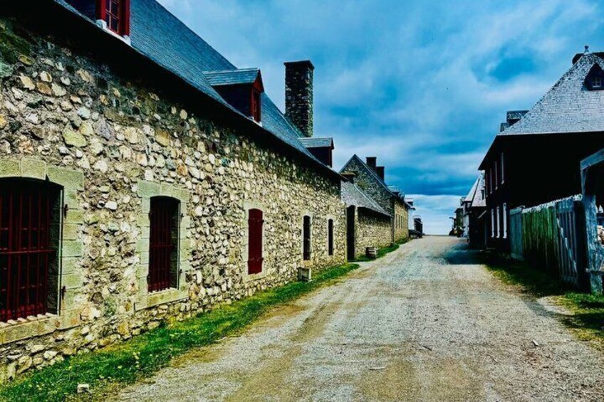 A stone building with red shutters, a gravel road, and a clear sky. 4