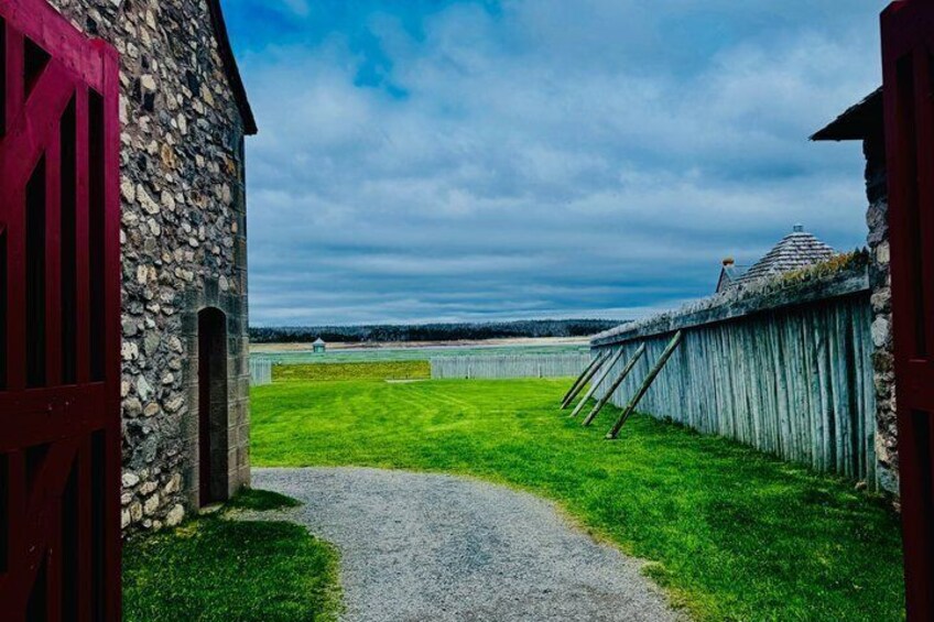 A stone building with a red door, a grassy field, and a wooden fence. 5