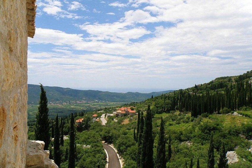 Un paisaje montañoso con una carretera serpenteante, abundante vegetación y edificios a lo lejos. 5