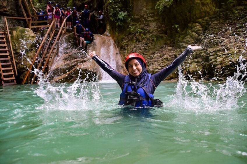 A person in a blue wetsuit and red helmet splashing water in a river. 1