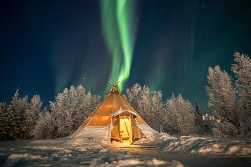 Et snæverklet landskab med et oplyst telt og nordlys i baggrunden. 2